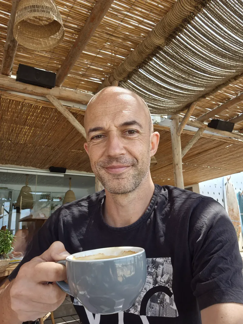 Lee Sykes smiling and holding a coffee